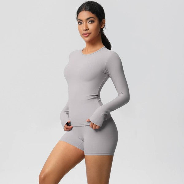 Woman in gray long-sleeve top and shorts against a plain light background.