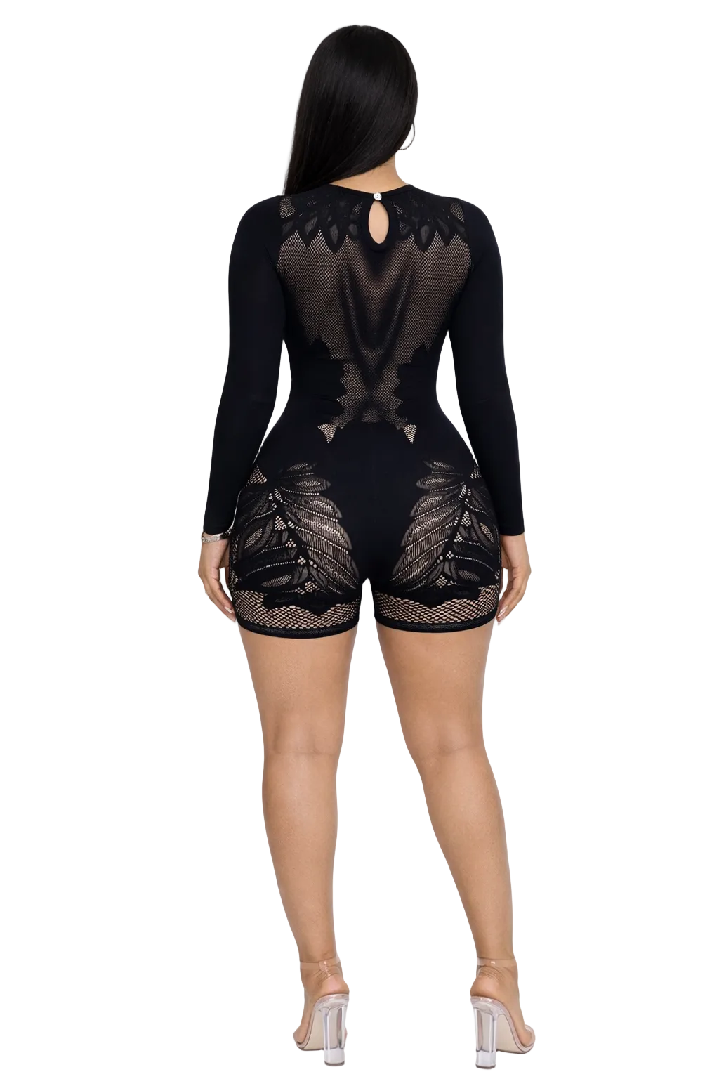 Woman in a black, long-sleeve mesh romper with intricate lace design, wearing clear heels.