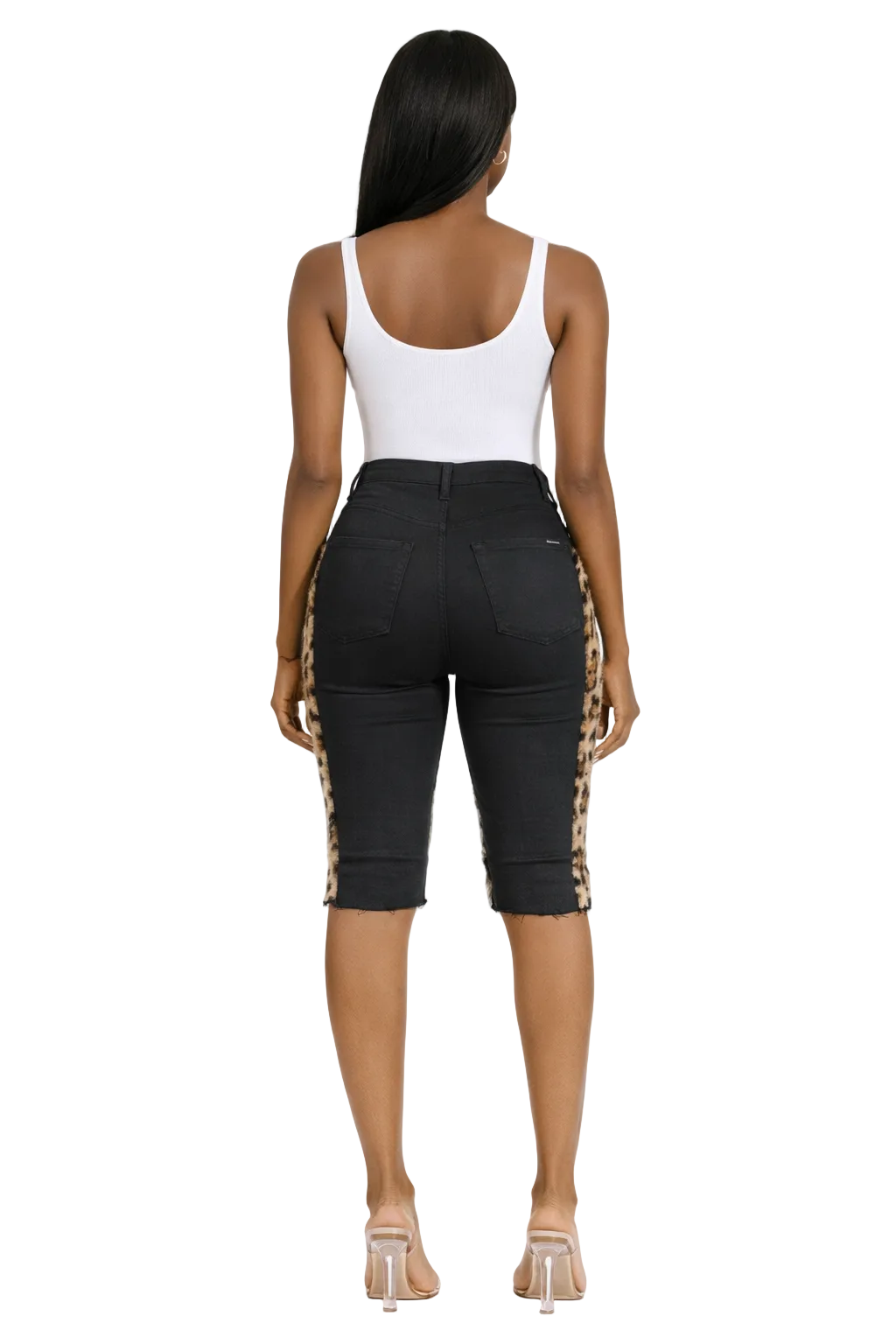 Woman in a white tank top and black shorts with leopard print sides, wearing clear heels.