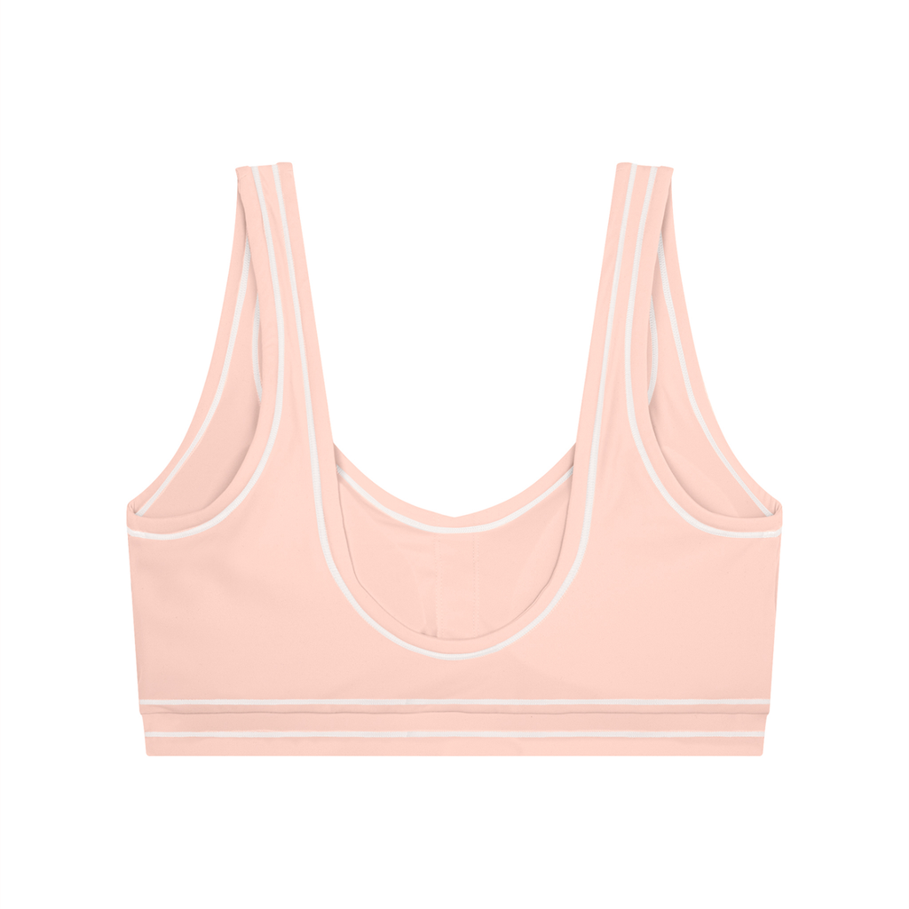 Peach-colored sports bra with white trim, double straps, and a scoop neckline.