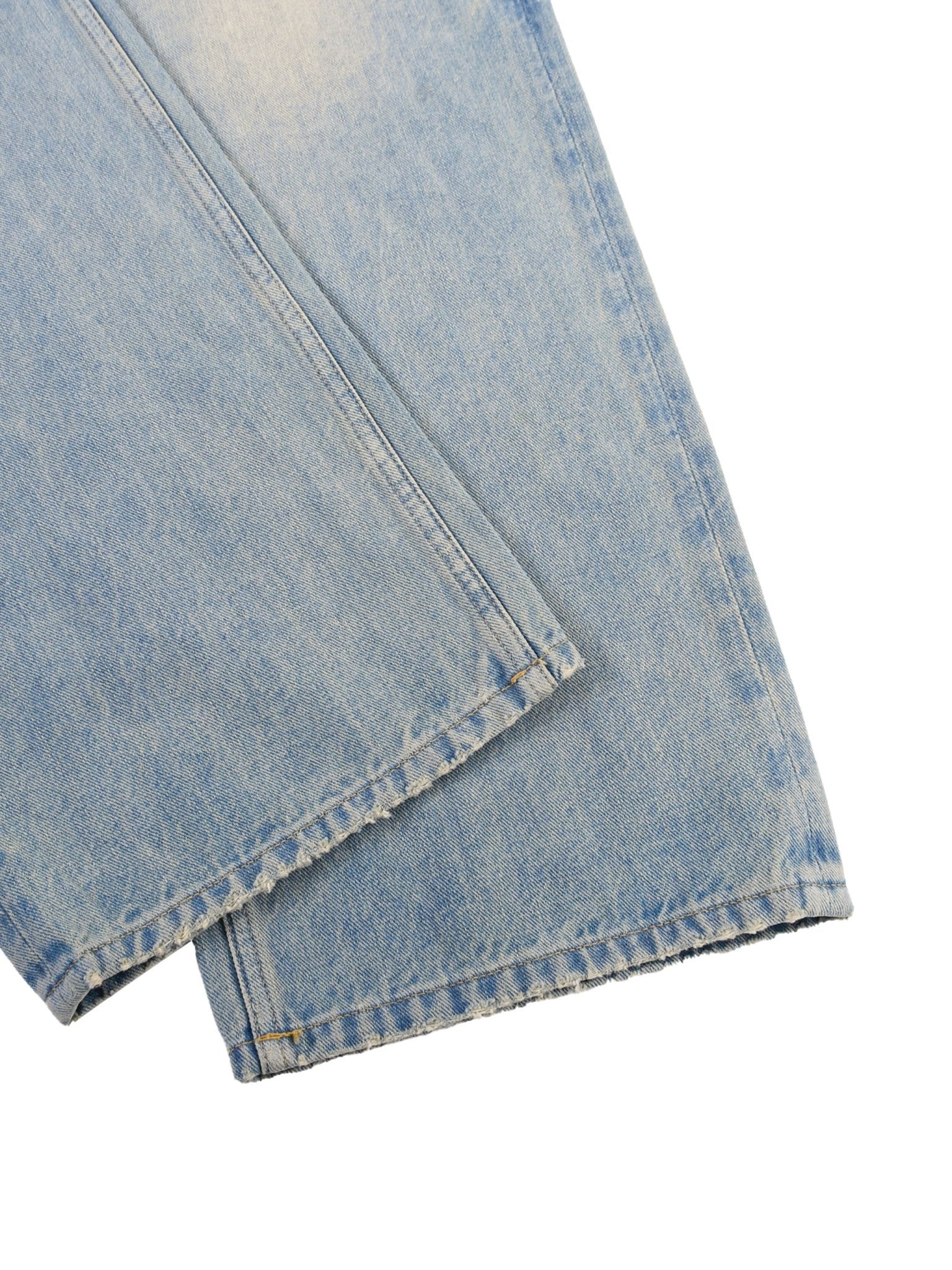 Close-up of faded blue denim jeans with frayed edges and visible stitching.