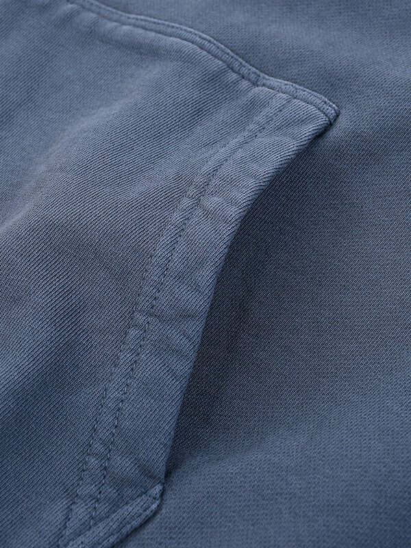 Close-up of a blue fabric with visible stitching and a partially visible pocket.