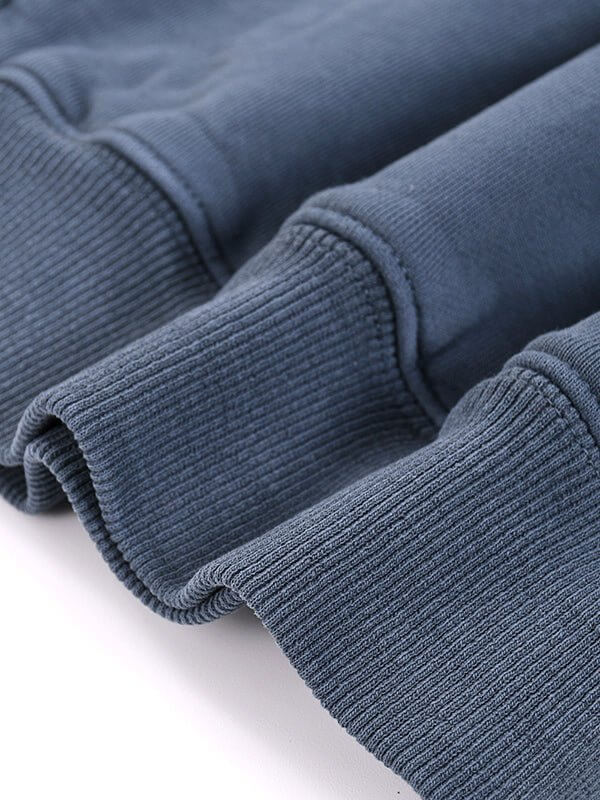 Close-up of folded blue ribbed fabric sleeves on a garment, showing texture and stitching.