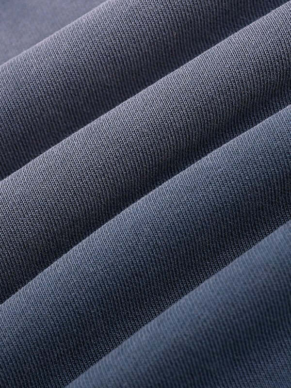 Close-up of blue ribbed fabric with diagonal folds showcasing texture and subtle shading.