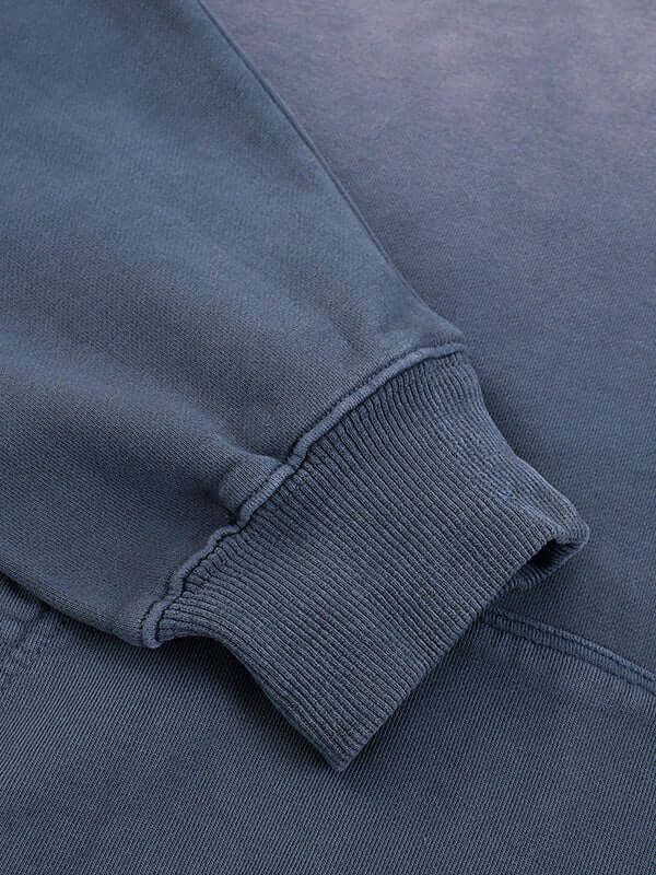 Dark blue sweatshirt sleeve with ribbed cuff detail.