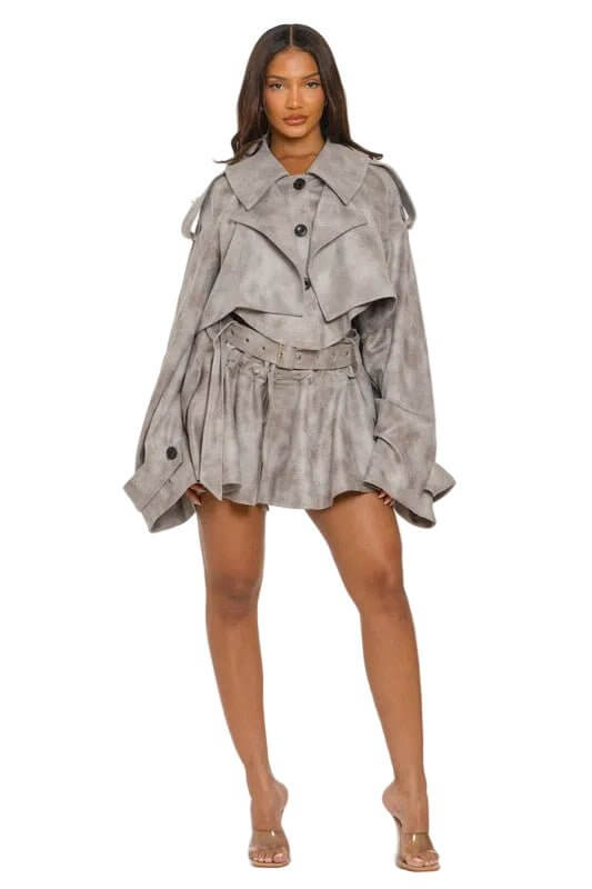 Woman in oversized gray jacket and skirt with belt, standing on a white background.