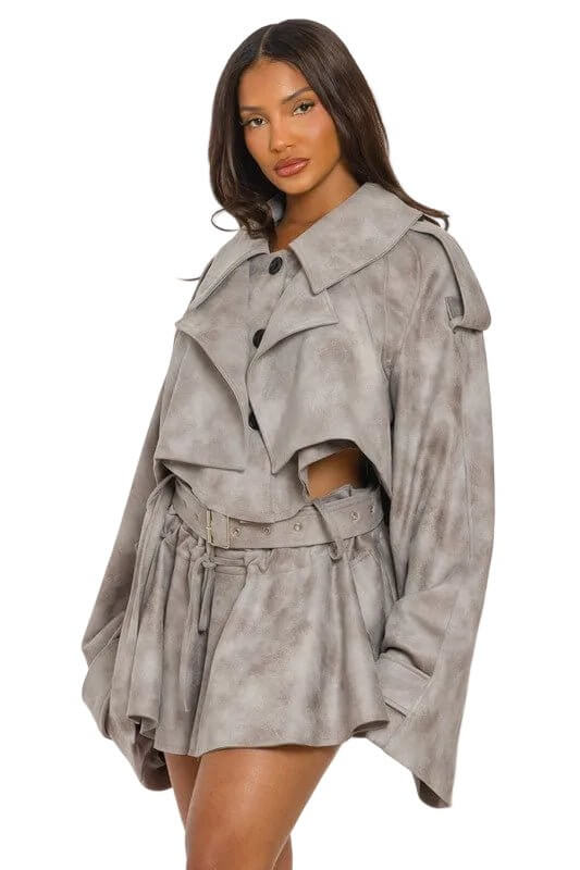 Woman in a gray belted coat with large collar and wide sleeves, standing against a white background.