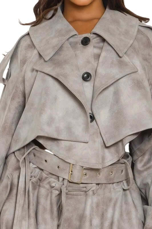 Woman wearing a light gray belted trench coat with large buttons and a wide collar.