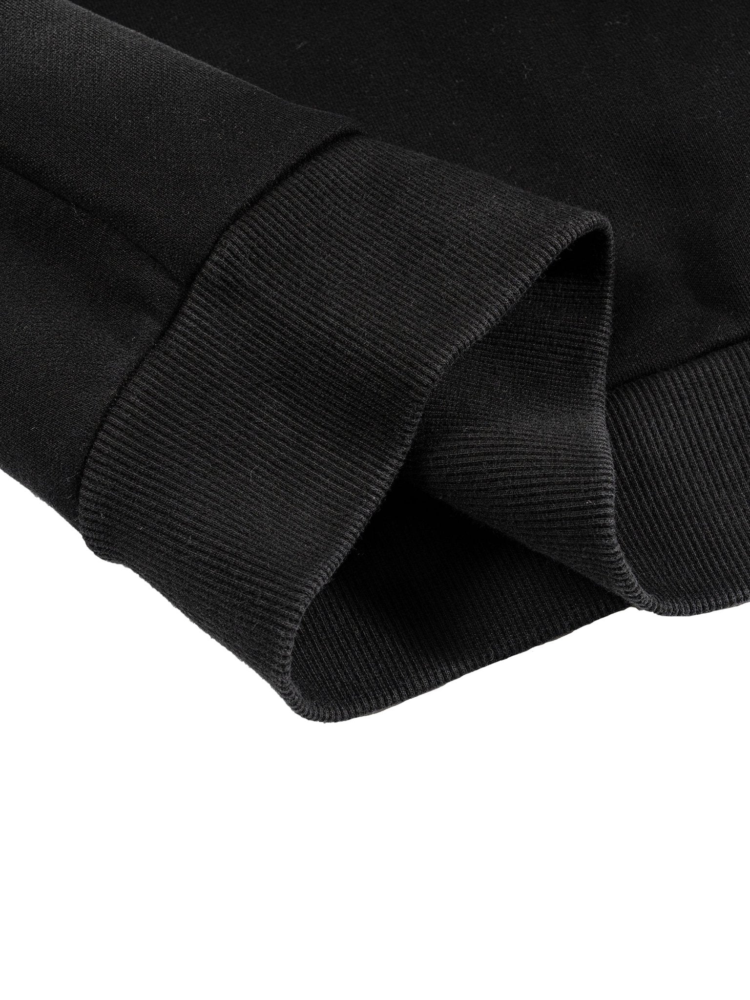 Close-up of a black fabric sleeve with ribbed cuffs on a white background.