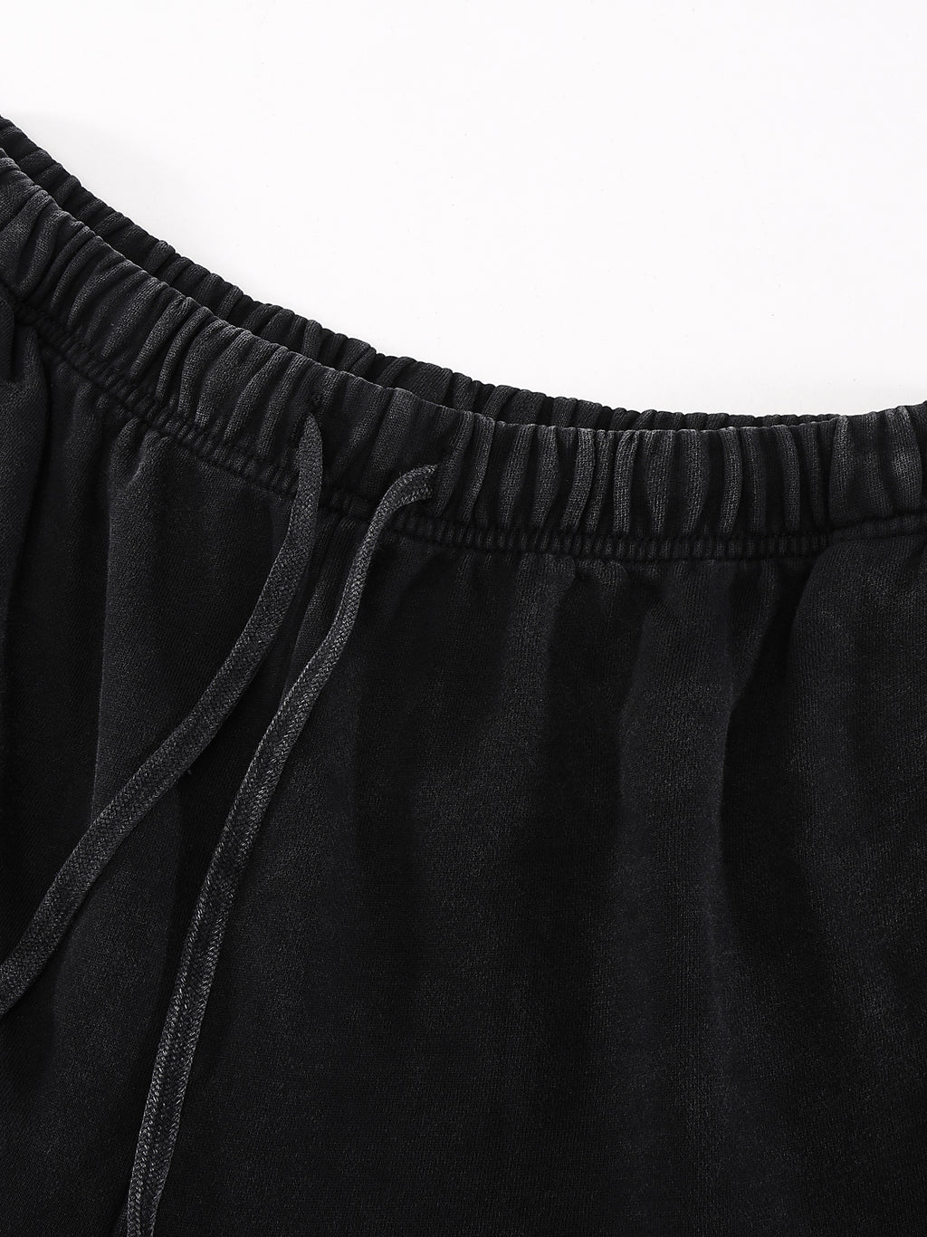 Black elastic waistband with drawstring on soft fabric, close-up view.