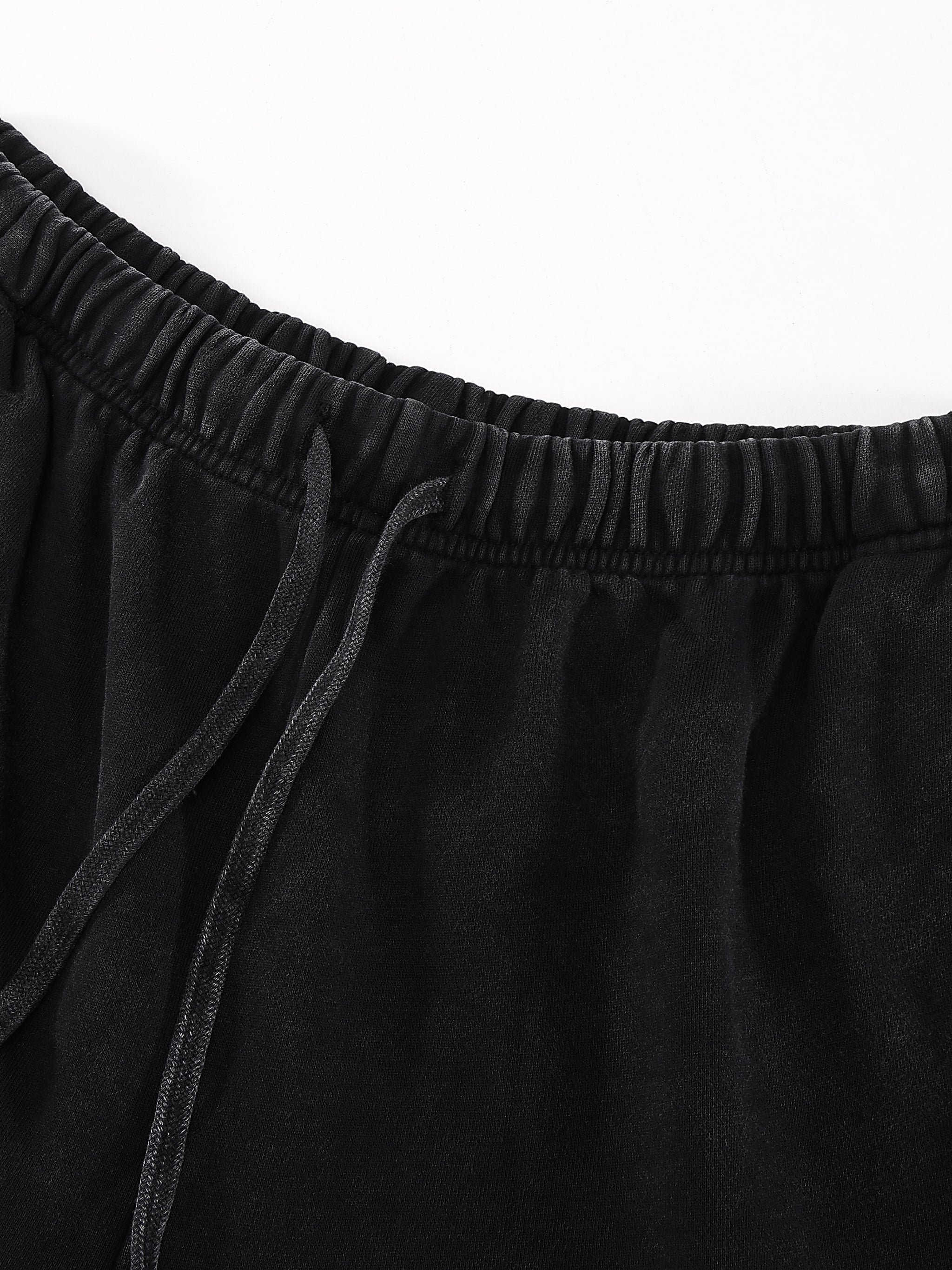 Black elastic waistband with drawstring on soft fabric, close-up view.