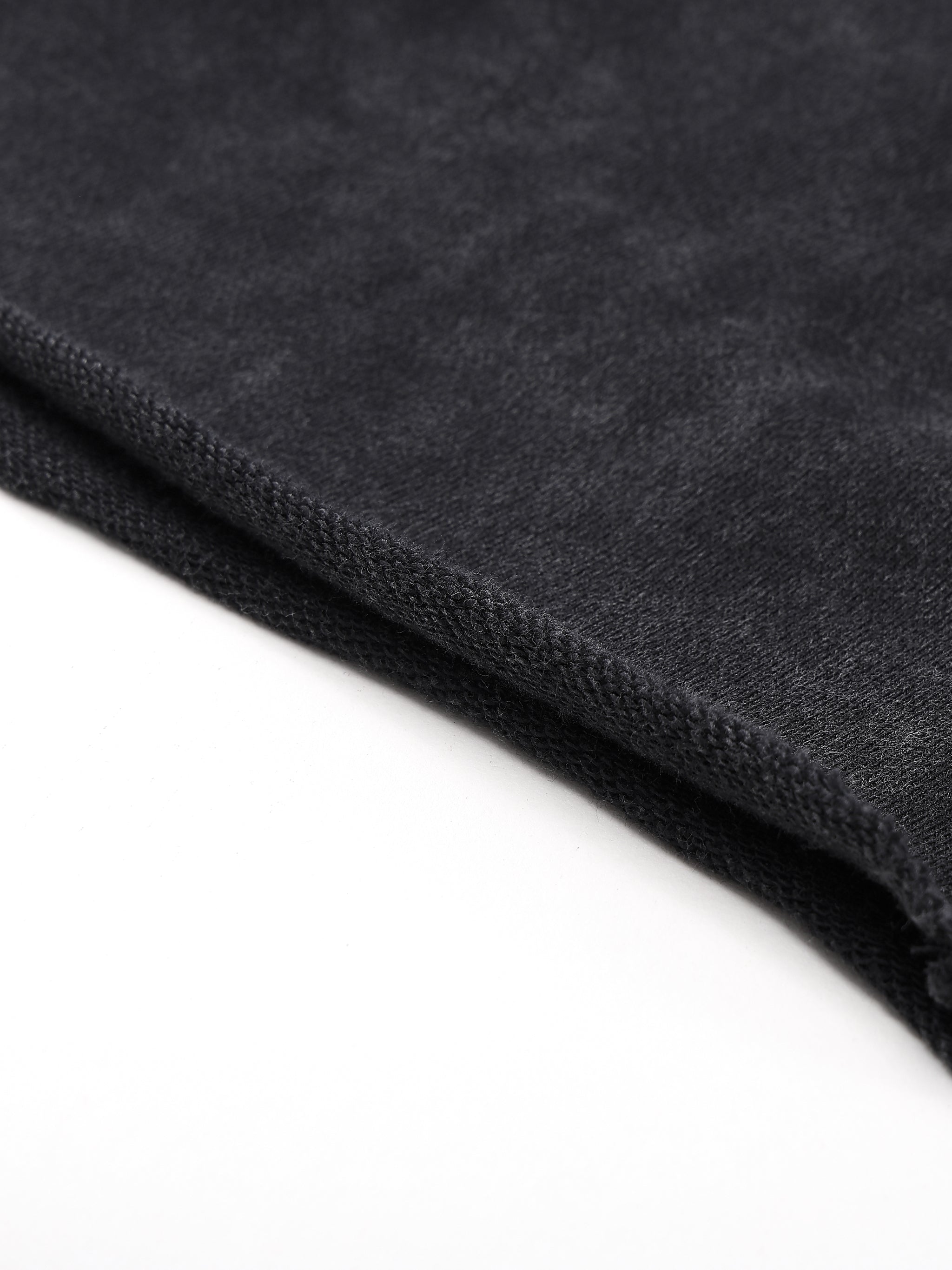 Close-up of dark gray textured fabric with a folded edge on a white background.