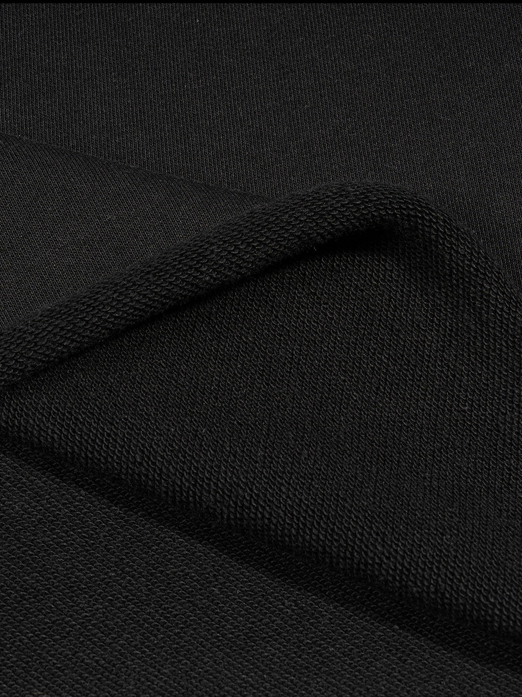 Close-up of folded black fabric with a smooth texture and visible weave pattern.