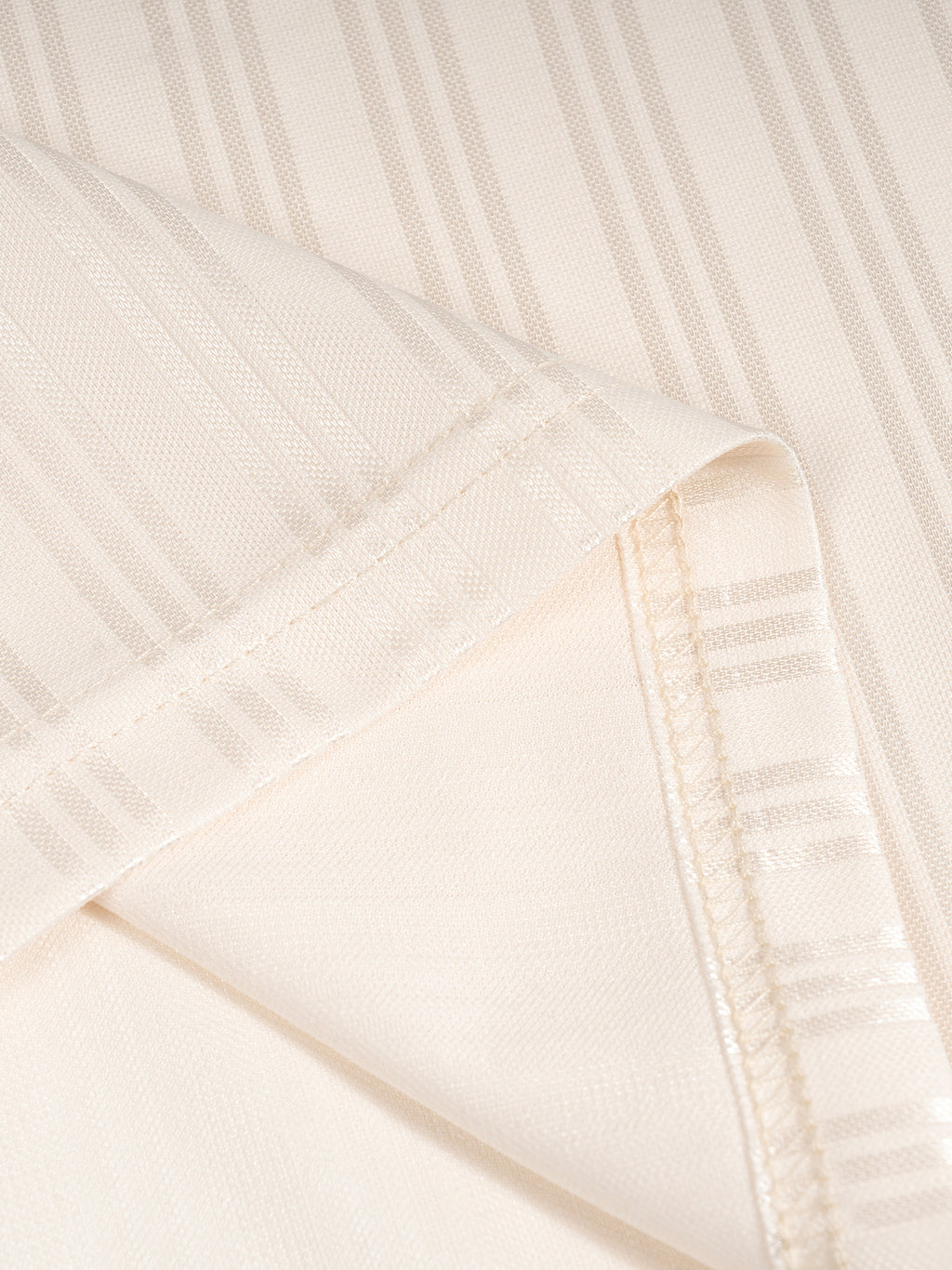 Close-up of beige fabric with vertical stripes and visible seams.