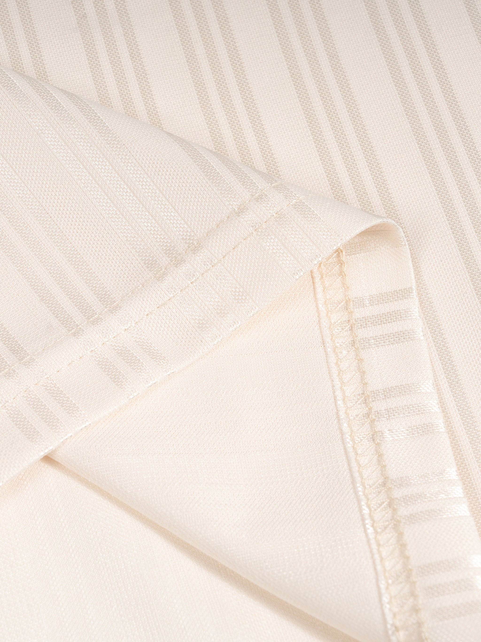Close-up of beige fabric with vertical stripes and visible seams.
