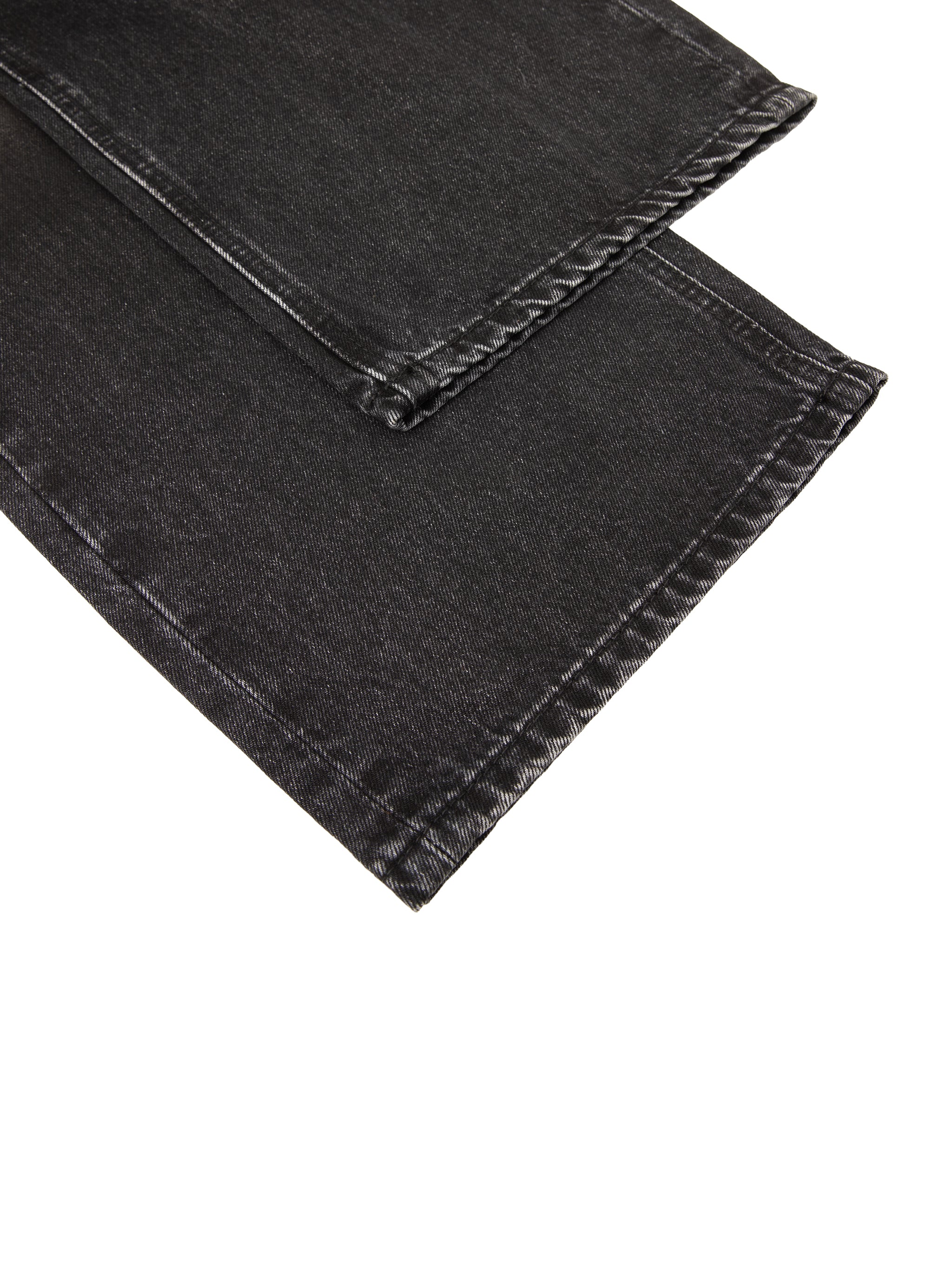 Close-up of black denim fabric with visible stitching and texture on the edges.