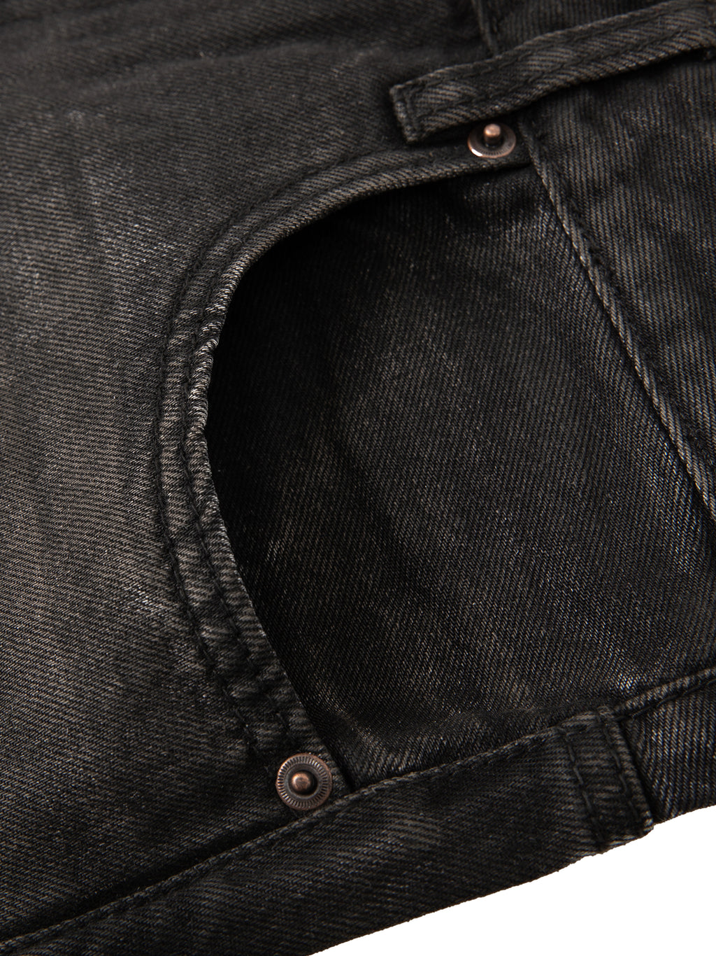 Close-up of a black denim pocket with rivets, showing texture and stitching details.