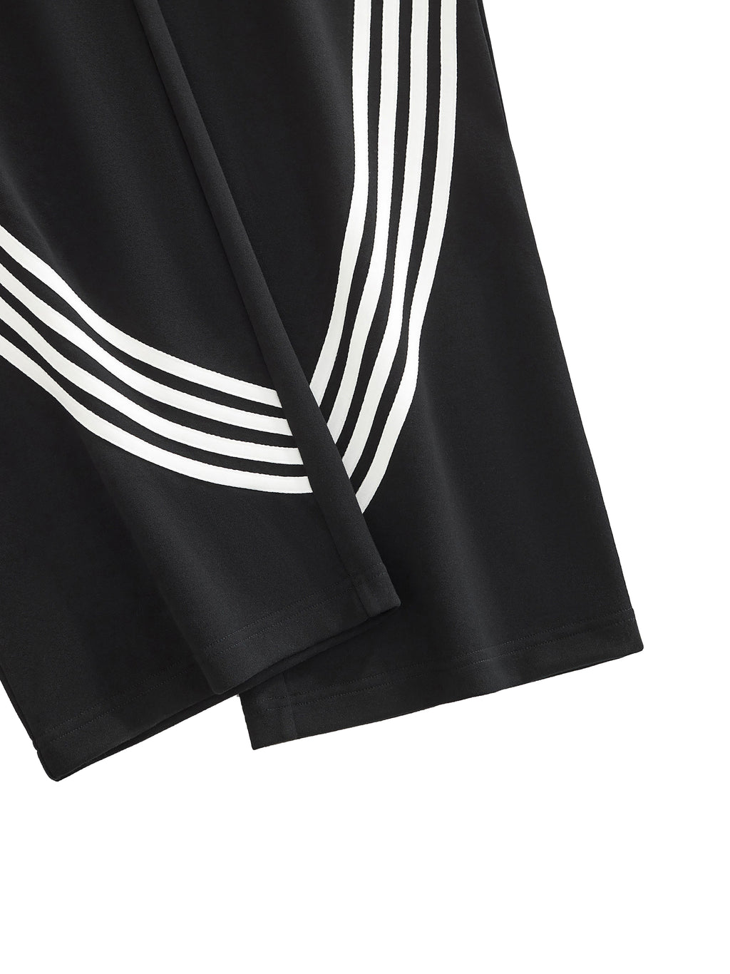 Black fabric with bold white curved stripes, showing part of pants or shorts.