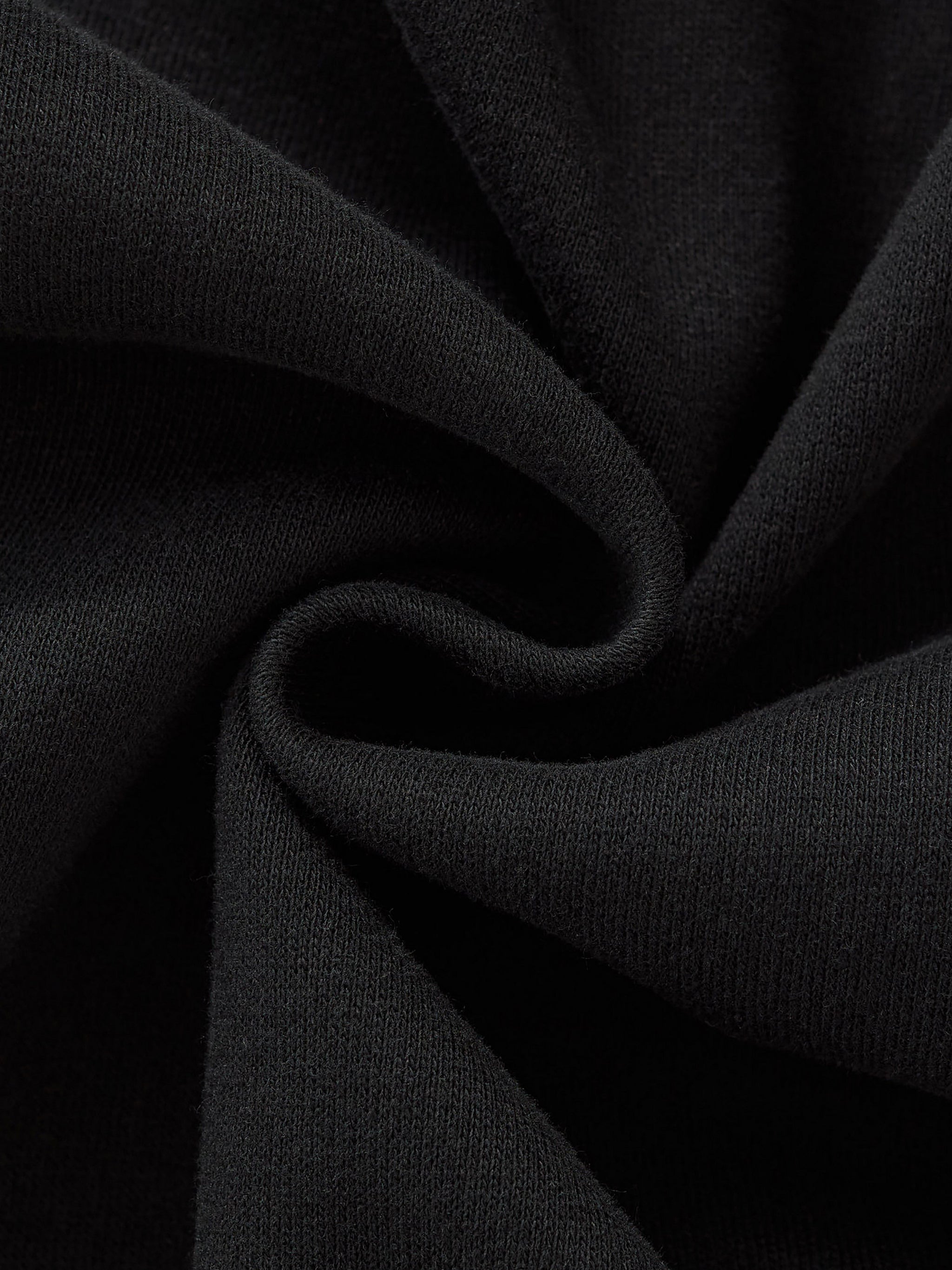 Close-up of black fabric twisted in a spiral, showcasing its soft texture and dark color.