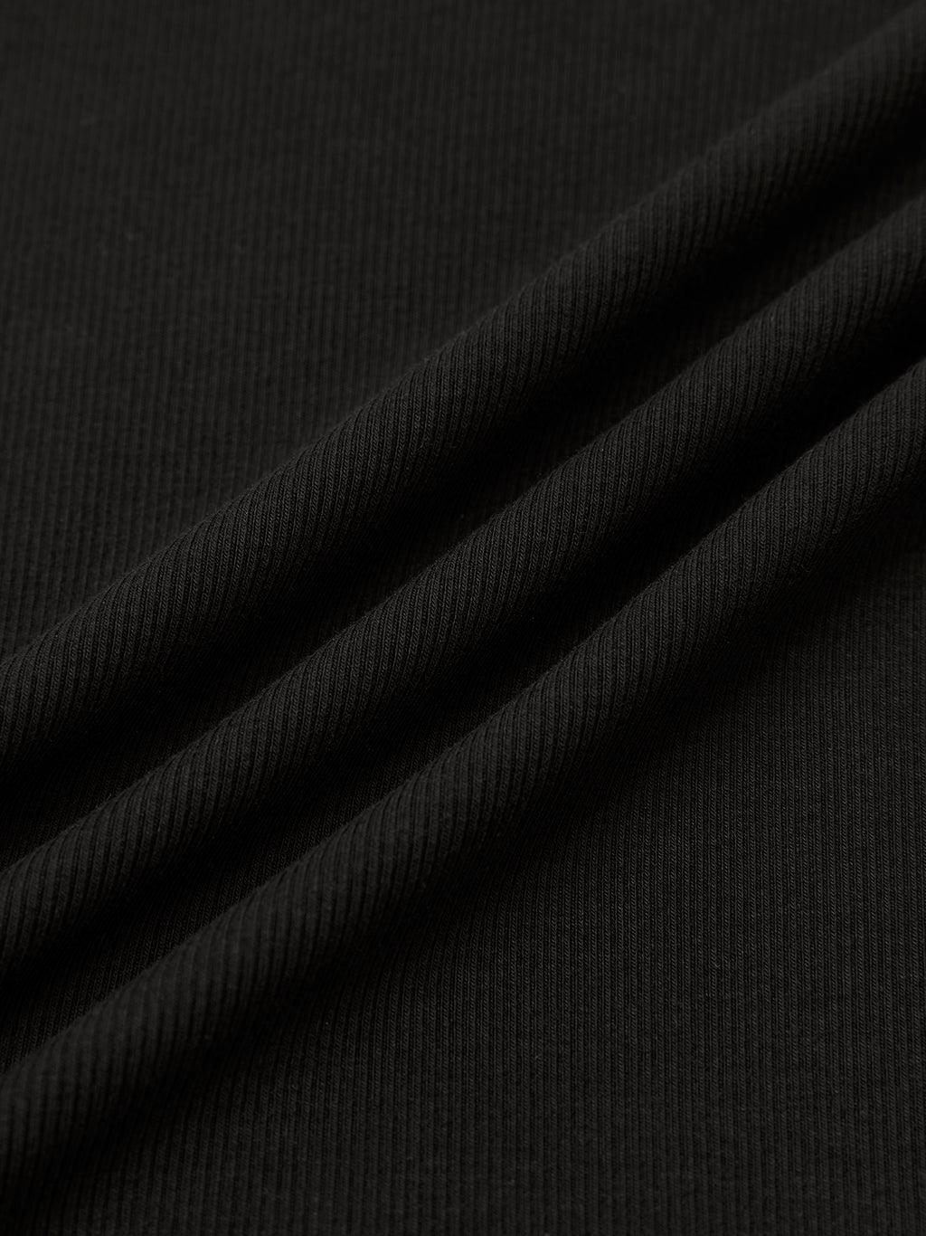 Close-up of folded black ribbed fabric with a soft texture and diagonal ridges.