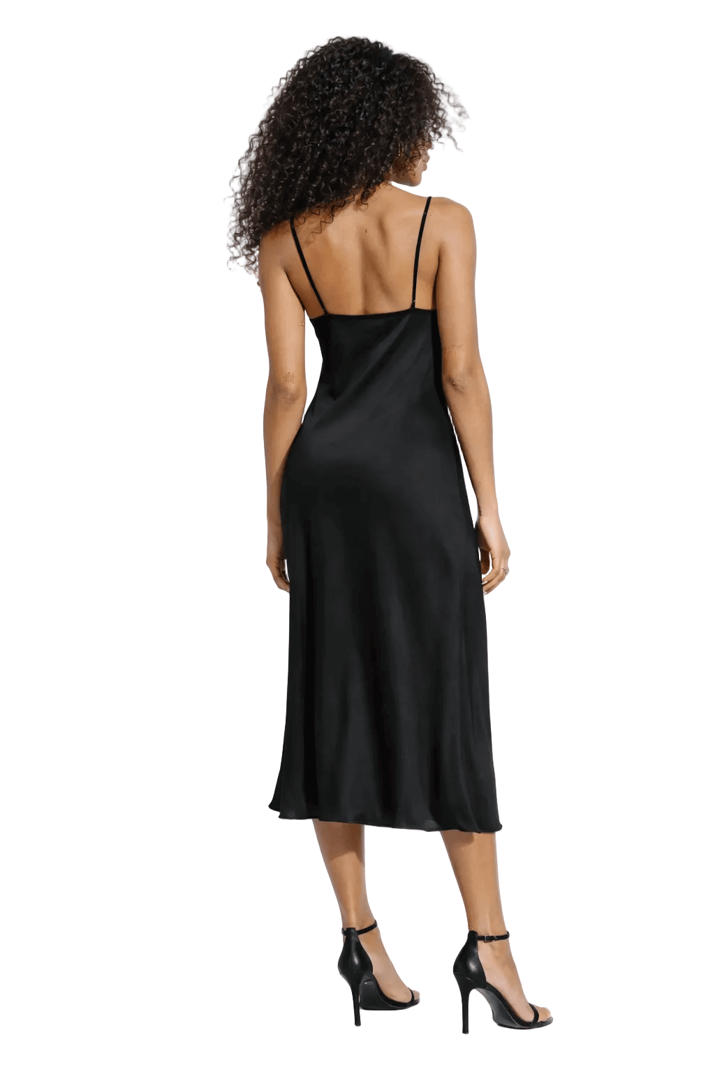 Woman in a black dress with thin straps, curly hair, black high heels, viewed from the back.