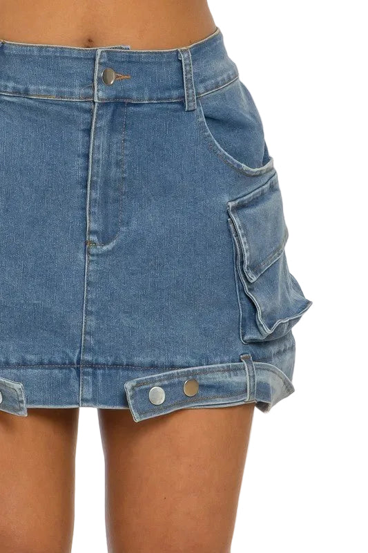 Denim mini skirt with large side pocket, belt loops, and silver button details on hem.